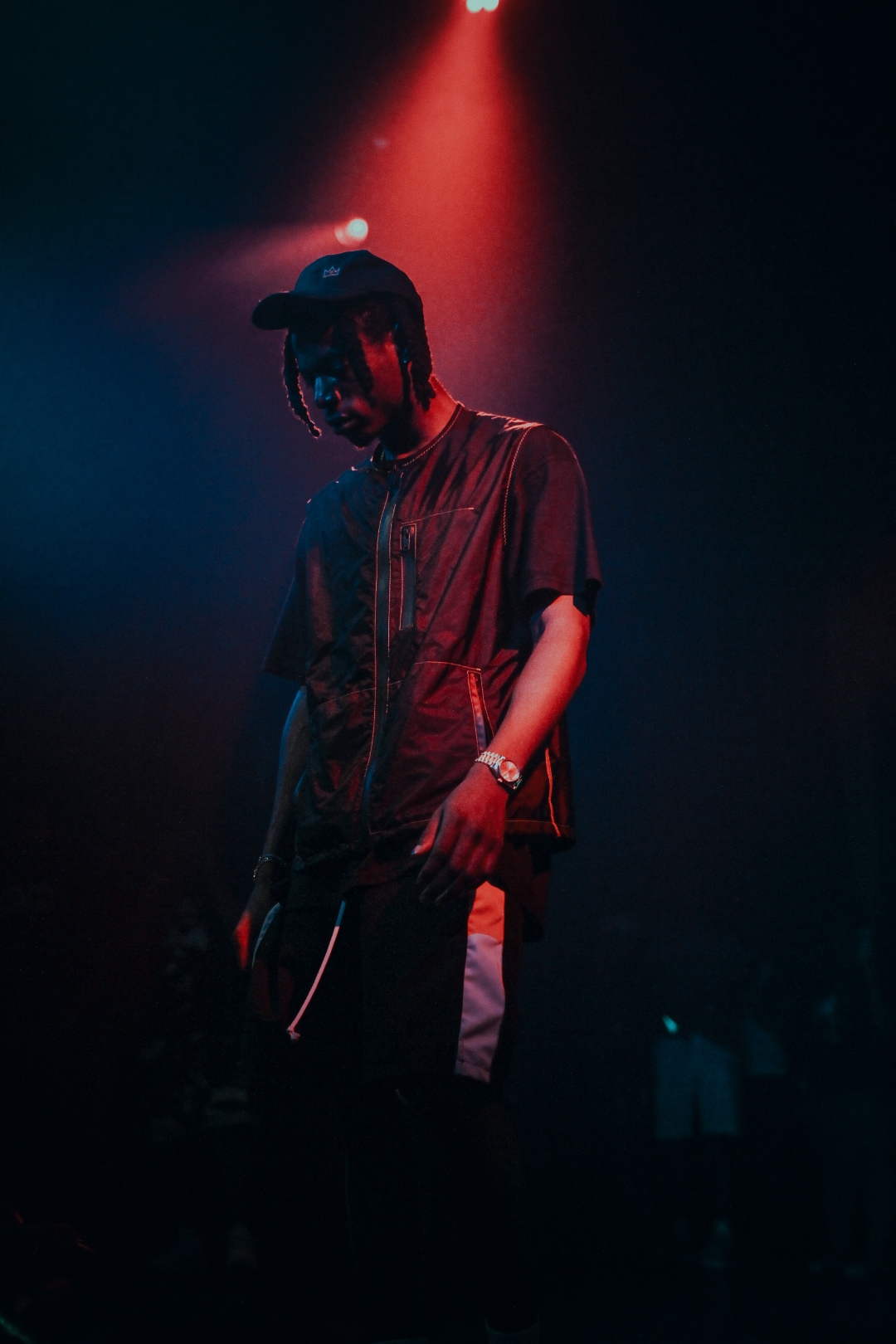 J. Cole under red spotlight in short-sleeve zip